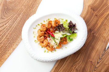 Fried shrimps in a plate on a wooden background.