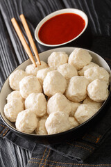 Bakso ayam Recipe Indonesian Meatballs from chicken with sauce close up in the bowl on the table. Vertical