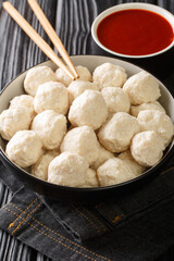 Homemade Indonesian chicken meatballs bakso ayam with sauce close up in the bowl on the table. Vertical