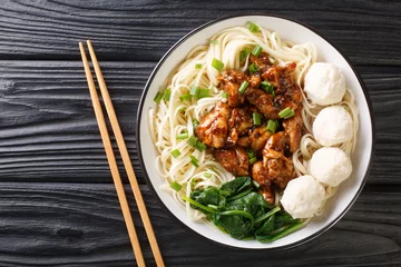 Foto op Canvas Mie Ayam Pangsit is a delicious Indonesian homemade recipe for noodles, chicken, meatballs bakso closeup in the bowl on the table. Horizontal top view from above © FomaA