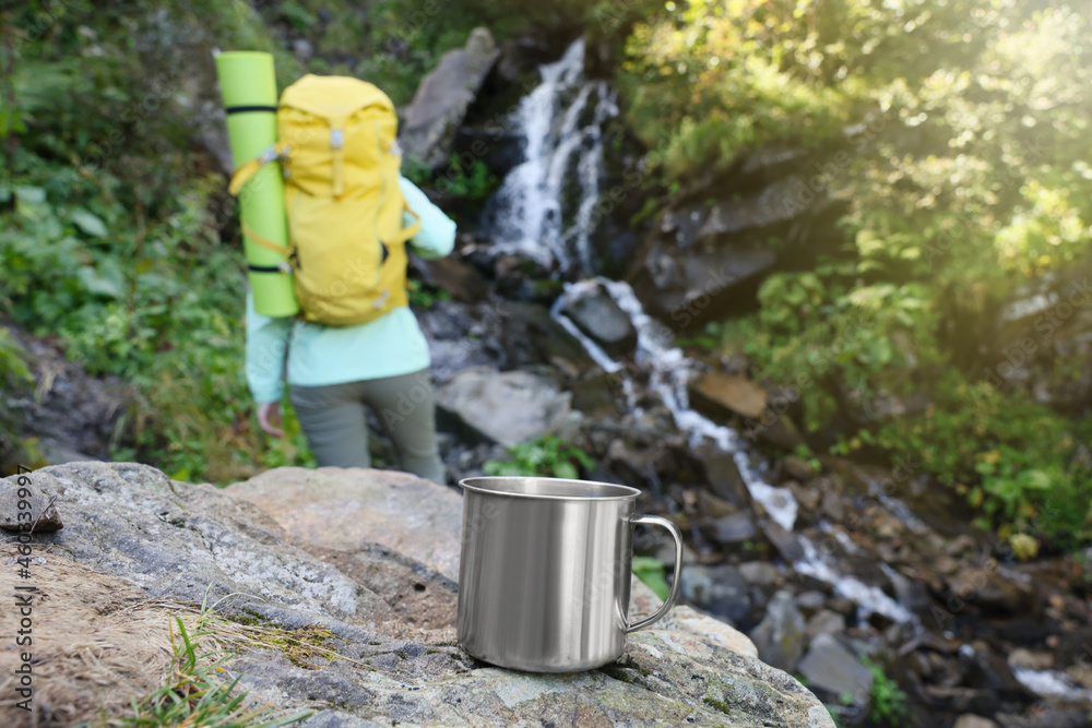 Sticker Tourist near waterfall in mountains, focus on cup