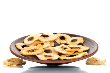 Several organic apple chips on a clay dish, close-up, isolated on white.