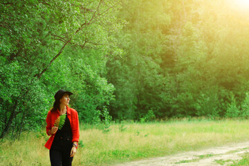 a woman in a hat walks through the forest in summer. outdoor recreation from the hustle and bustle...
