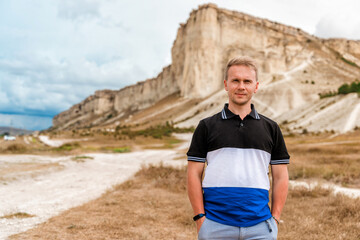 Young man standing and looking out over a huge white rock, concept of travel and freedom, Crimea