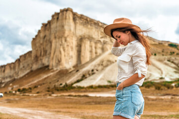 A young woman in a hat at the foot of a White Rock in the Crimea. A beautiful wild west scene with...