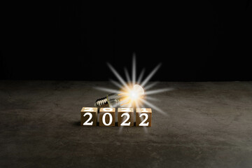 A bright light bulb on the work table. Concept of a startup that drives the economy, finance, banking, forward, future, glowing, startup, strategy, success, 2021 to 2022, Blurred, black background