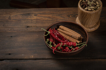 Dried chili peppers and cinnamon pods in an earthenware bowl