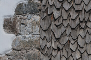 sunburned wooden shingles next stone wall on a facade