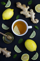 Top view of tea in the white cup with lemon, ginger and honey on the wooden background. Copy space.
