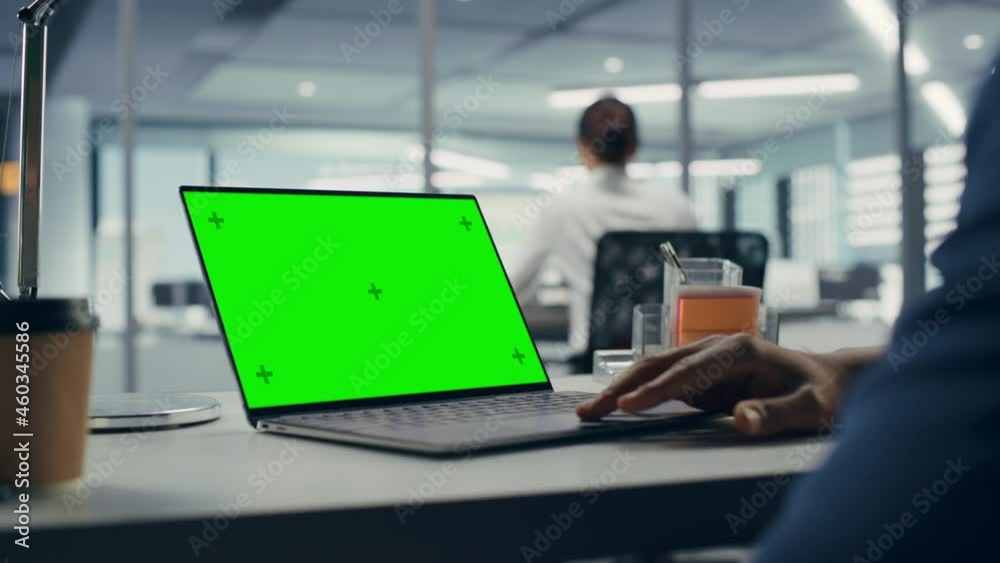 Poster successful black businessman sitting at desk working on green screen laptop computer in office. anon