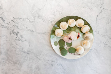 White macaroons are on a plate. Delicious light cookies on a plate on a light background. Bakery