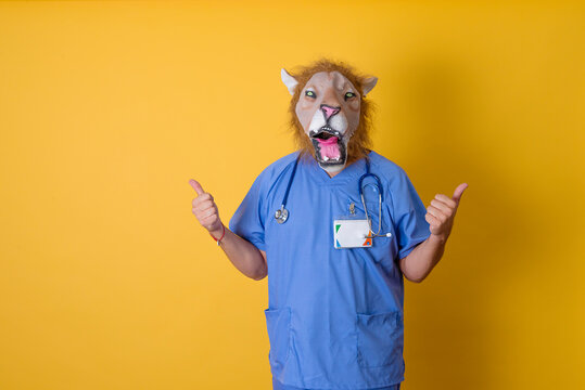 A doctor with lion mask in front making the ok sign with his hands. Yellow background.