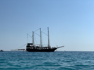 Fototapeta na wymiar Sailing boat on the high seas. The yacht sails along the seashore. Small ship against the blue sky