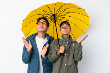 Young mixed race couple holding an umbrella isolated on white background frustrated by a bad situation