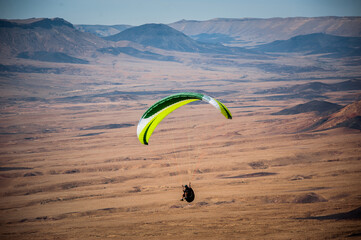 A paraglider soars over the Israeli desert