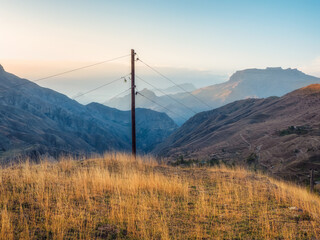 Network of wires and telegraph poles on the autumn foggy mountain hills. Atmospheric mountain foggy landscape in Dagestan.