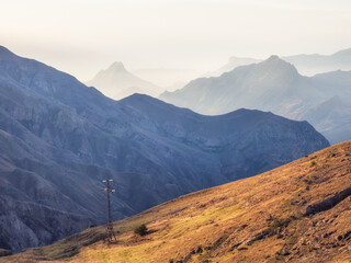 Network of wires and telegraph poles on the autumn foggy mountain hills. Atmospheric mountain foggy landscape in Dagestan.