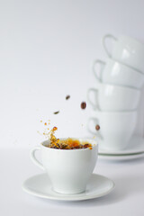 Dive into the energizing moment of coffee splash, captured against a minimalistic setting of pure white and a tower of ceramic cups waiting their turn.