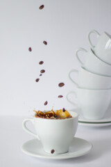 Witness the dynamic dance of coffee, with droplets suspended in mid-air, set against an elegant arrangement of white cups and scattered beans.