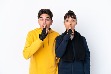 Young mixed race sport couple isolated on white background showing a sign of silence gesture putting finger in mouth