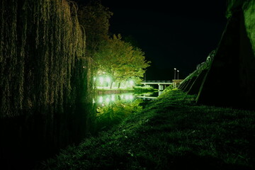 Beautiful night embankment near the river with green lights on a