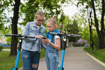 Mother and daughter using application on smartphone for sharing electric scooters