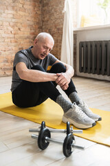 Elderly man relaxing after his fitness workout at home