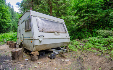 Abandoned travel trailer in the meadow with forest on background. Romania Transilvania 