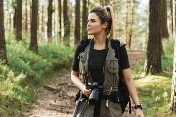 Woman hiker walking with a backpack and modern mirrorless camera