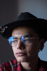 Young caucasian man portrait wearing a black hat and a plaid shirt with glassses
