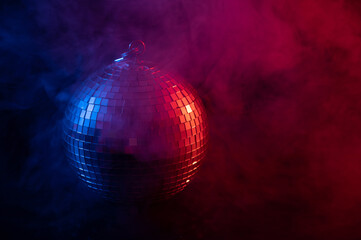 The disco ball is spinning in pink-blue smoke. Night life.