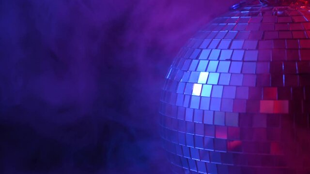 The disco ball is spinning in pink-blue smoke. Night life.