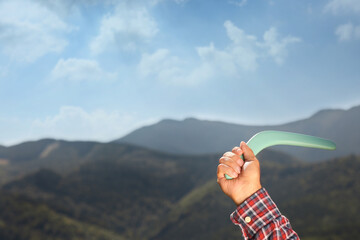 Man throwing boomerang in mountains, closeup. Space for text