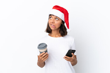 Young mixed race woman celebrating Christmas isolated on white background holding coffee to take away and a mobile while thinking something