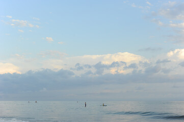 Fototapeta na wymiar Black Sea in Abkhazia. Small figures of surfers. Blue pastel sunset. Rest on the sea