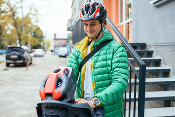 Unrecognizable man putting security helmet on cute boy at the street. Father puts his son a European man putting security helmet on cute boy at the street. Father puts his son a protective helmet for 