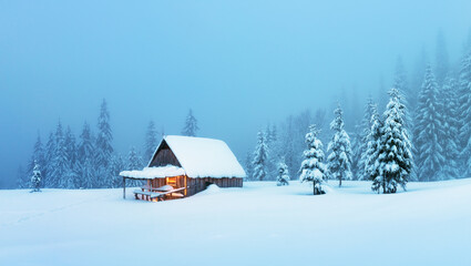 Fantastic winter landscape with glowing wooden cabin in snowy forest. Cozy house in Carpathian mountains. Christmas holiday concept - obrazy, fototapety, plakaty
