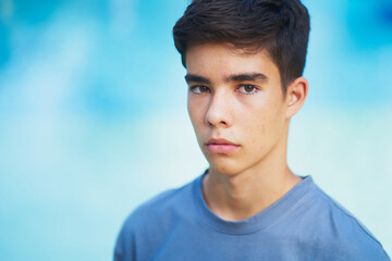 Close up portrait of a teenager model looking at camera against blue background