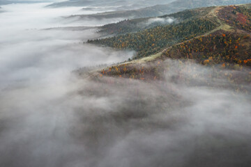 Amazing flowing morning fog in autumn mountains. Beautiful sunrise on background. Landscape photography