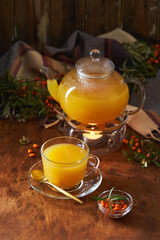 Glass teapot and sea buckthorn tea cup on wooden background