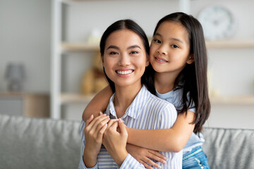 Togetherness concept. Happy asian mother and daughter hugging and smiling to camera, copy space