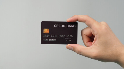 Hand is holding black credit card isolated on grey background.