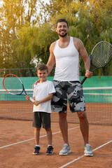 Fototapeta na wymiar Father with his son on tennis court