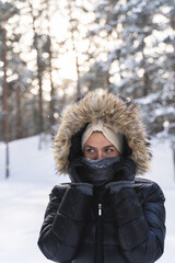 Fototapeta na wymiar Young woman wearing down jacket with a hoodie during cold winter day