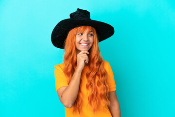 Young woman disguised as witch isolated on blue background looking to the side