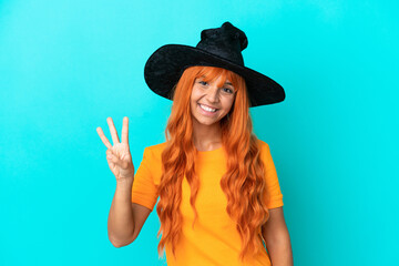 Young woman disguised as witch isolated on blue background happy and counting three with fingers