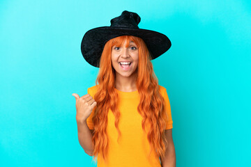 Young woman disguised as witch isolated on blue background pointing to the side to present a product