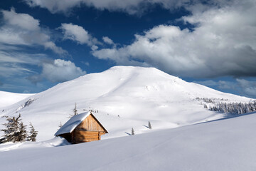 Fantastic winter landscape with wooden house in snowy mountains. Christmas holiday concept