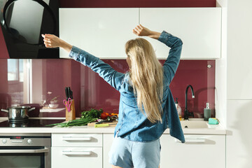 Fototapeta na wymiar Attractive woman dancing on the kitchen while cooking during sunny morning