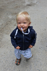 little blond child posing on the asphalt road